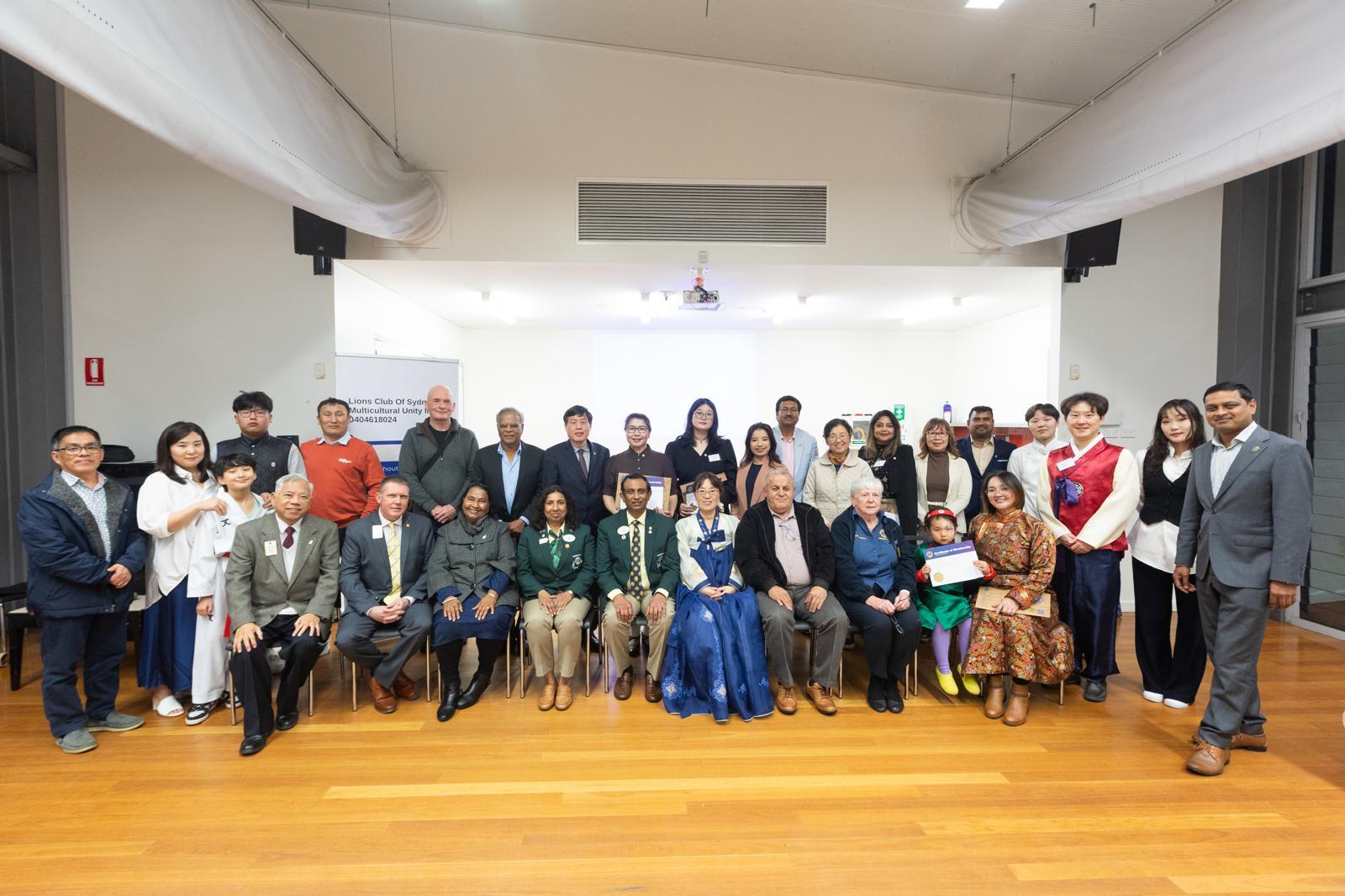 SMULC charter and induction night — the whole club and District 201N5 guests gathered for a group photo in front of the club banner, with members in traditional dress from many cultures