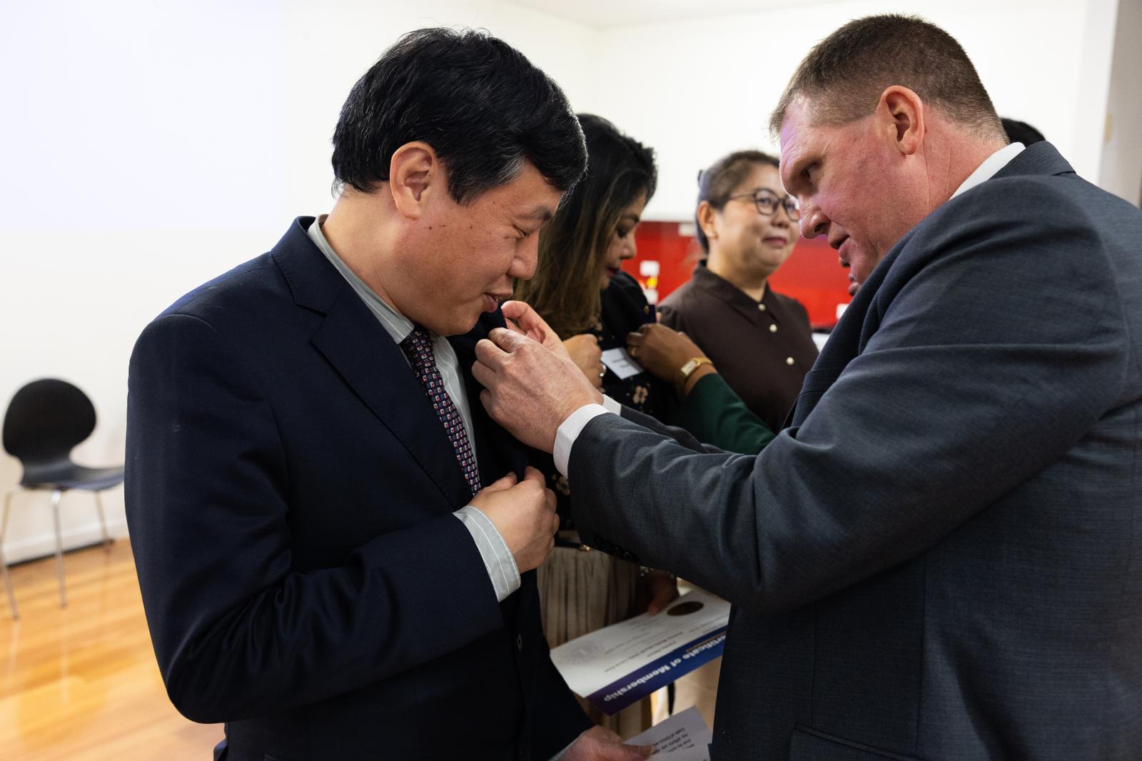 A District 201N5 officer pinning a Lions membership badge onto a new SMULC member during the induction ceremony