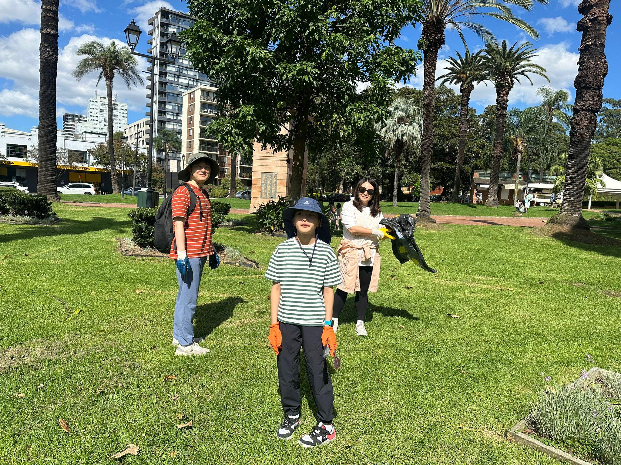 SMULC volunteers cleaning up a Sydney inner-city park with palm trees and city skyline behind