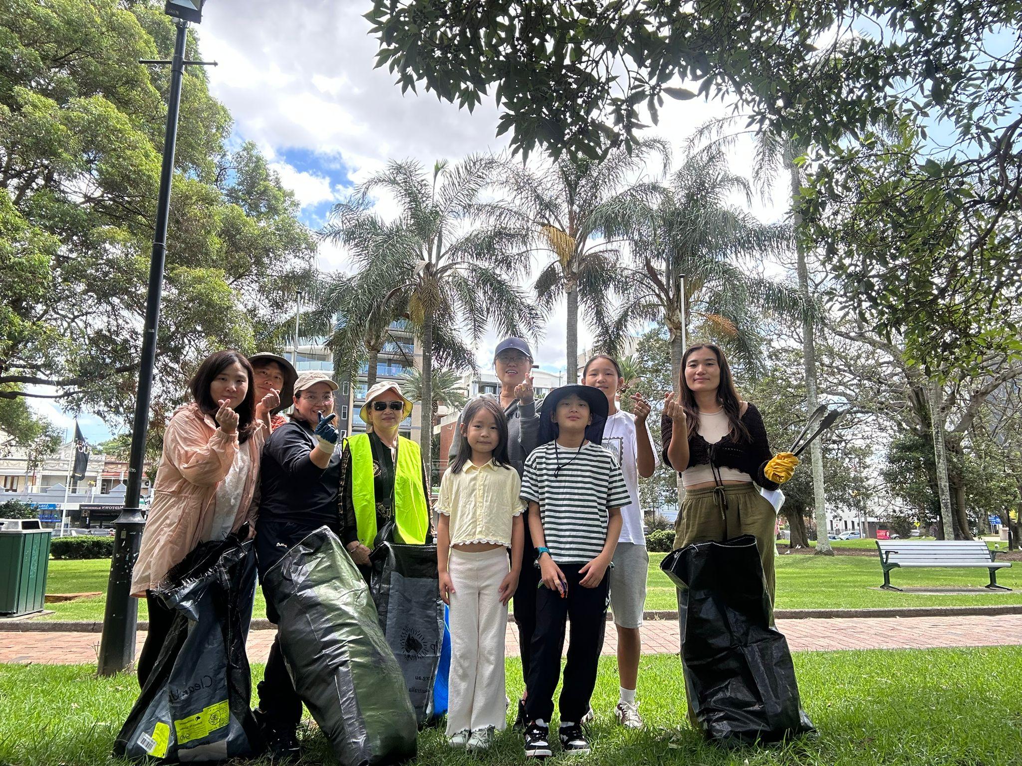 SMULC members and families posing after a Sydney park clean-up with filled rubbish bags