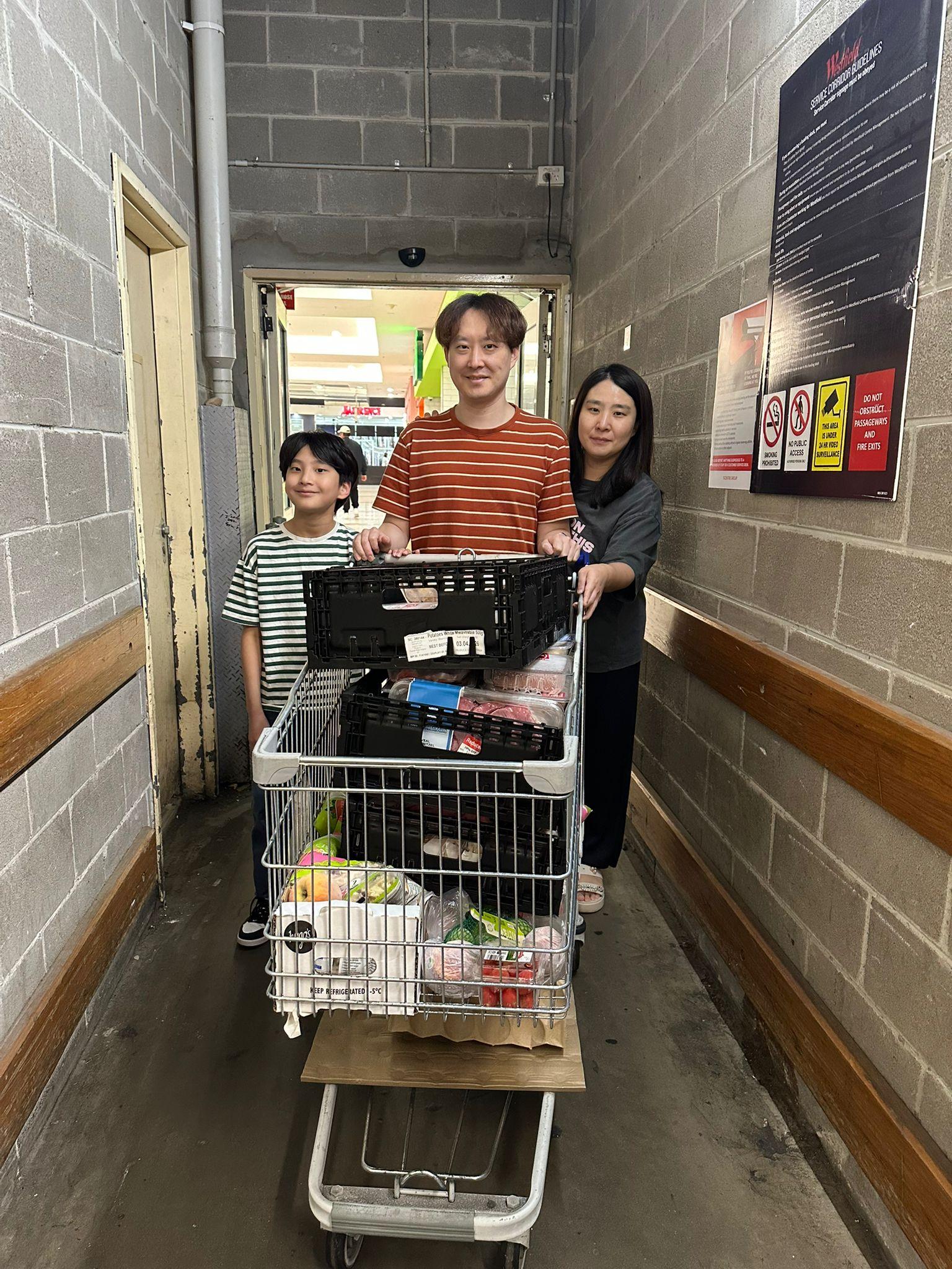 SMULC volunteers standing behind a shopping trolley piled with rescued food