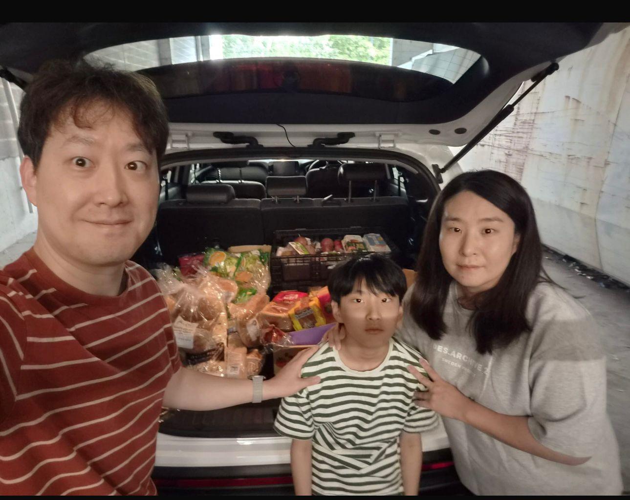 A family of SMULC volunteers with a car boot full of rescued groceries during a food rescue run