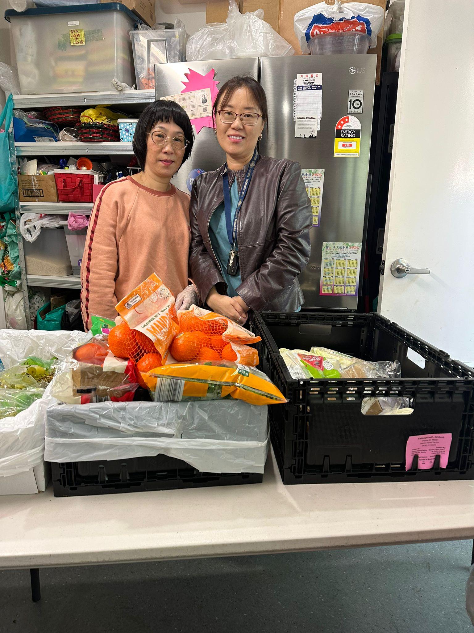 Two SMULC members sorting rescued fruit and bread into crates at a community food pantry